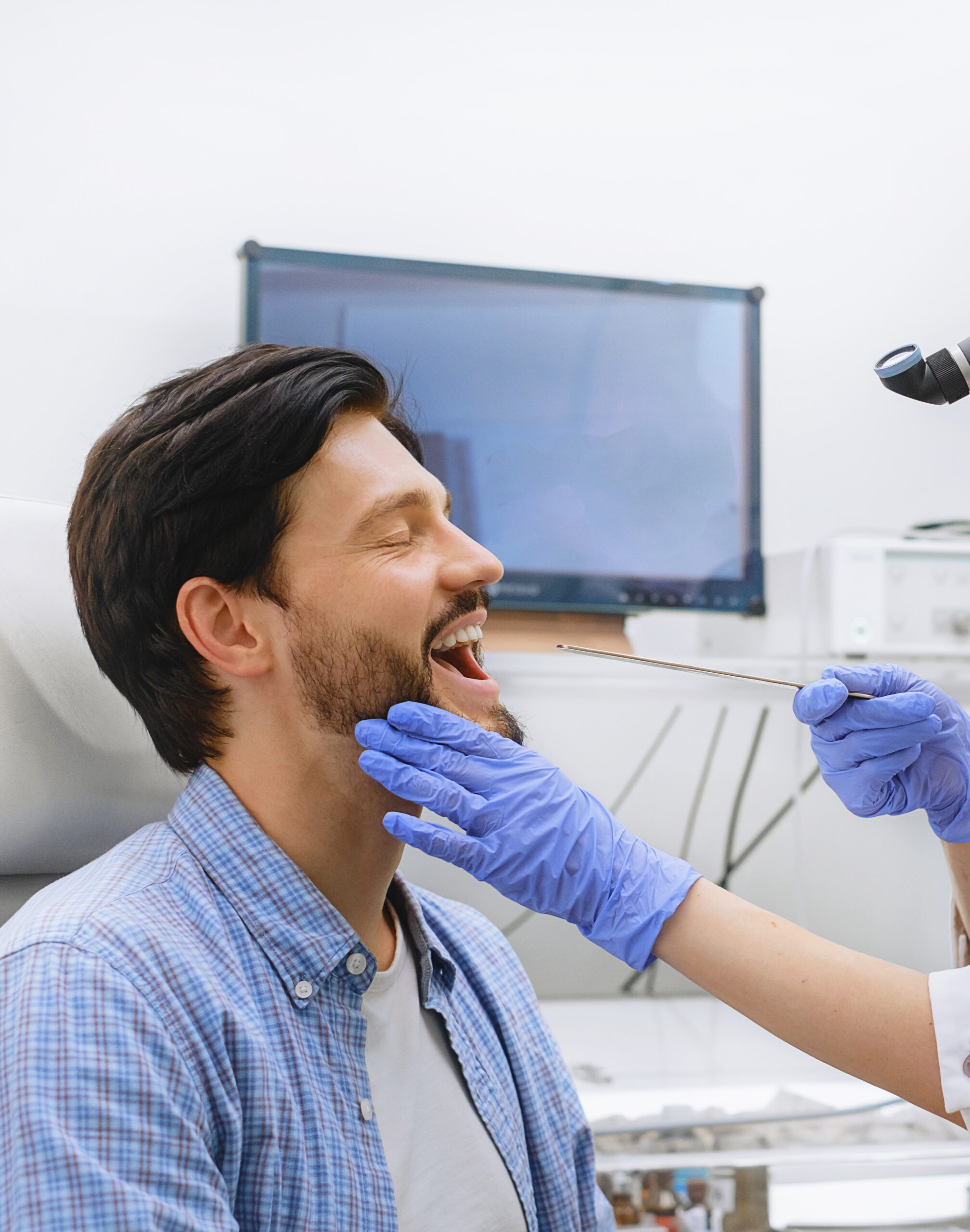 otolaryngologist performing oral examination of male patient